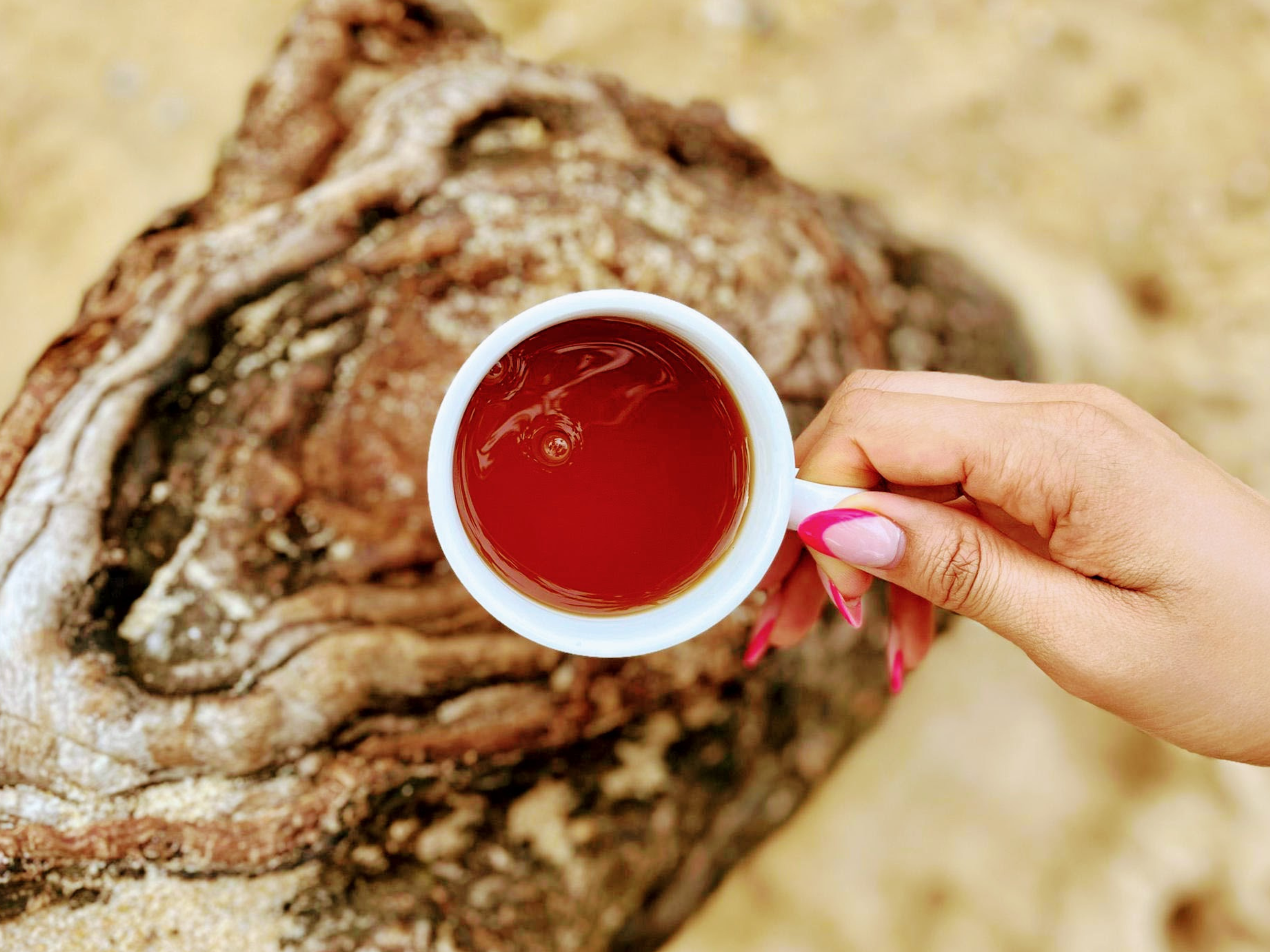 Holding a cup of SHE KITTY tea that provides relief for menopause symptoms.