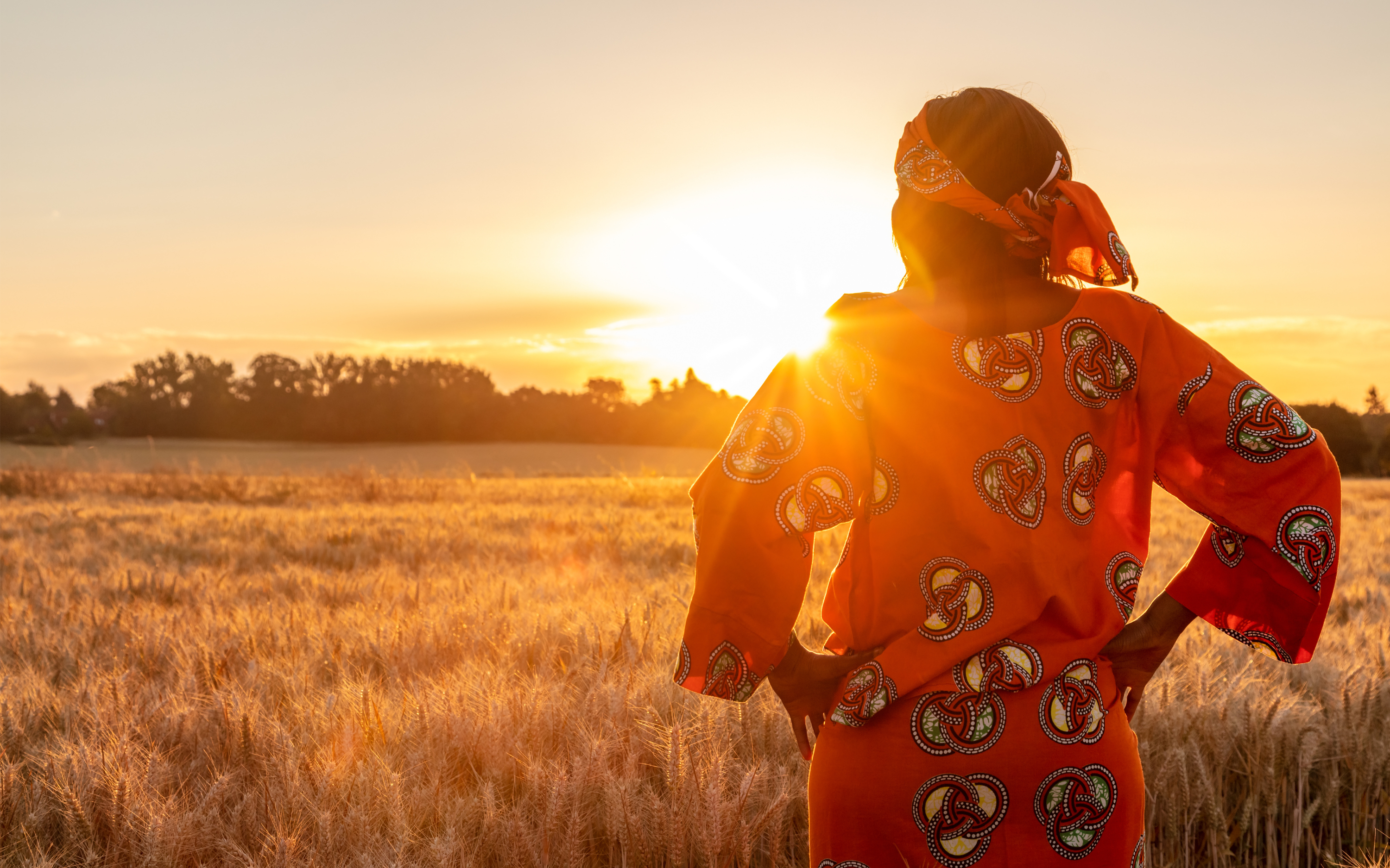 West African women looking out at the sunset over her farm.