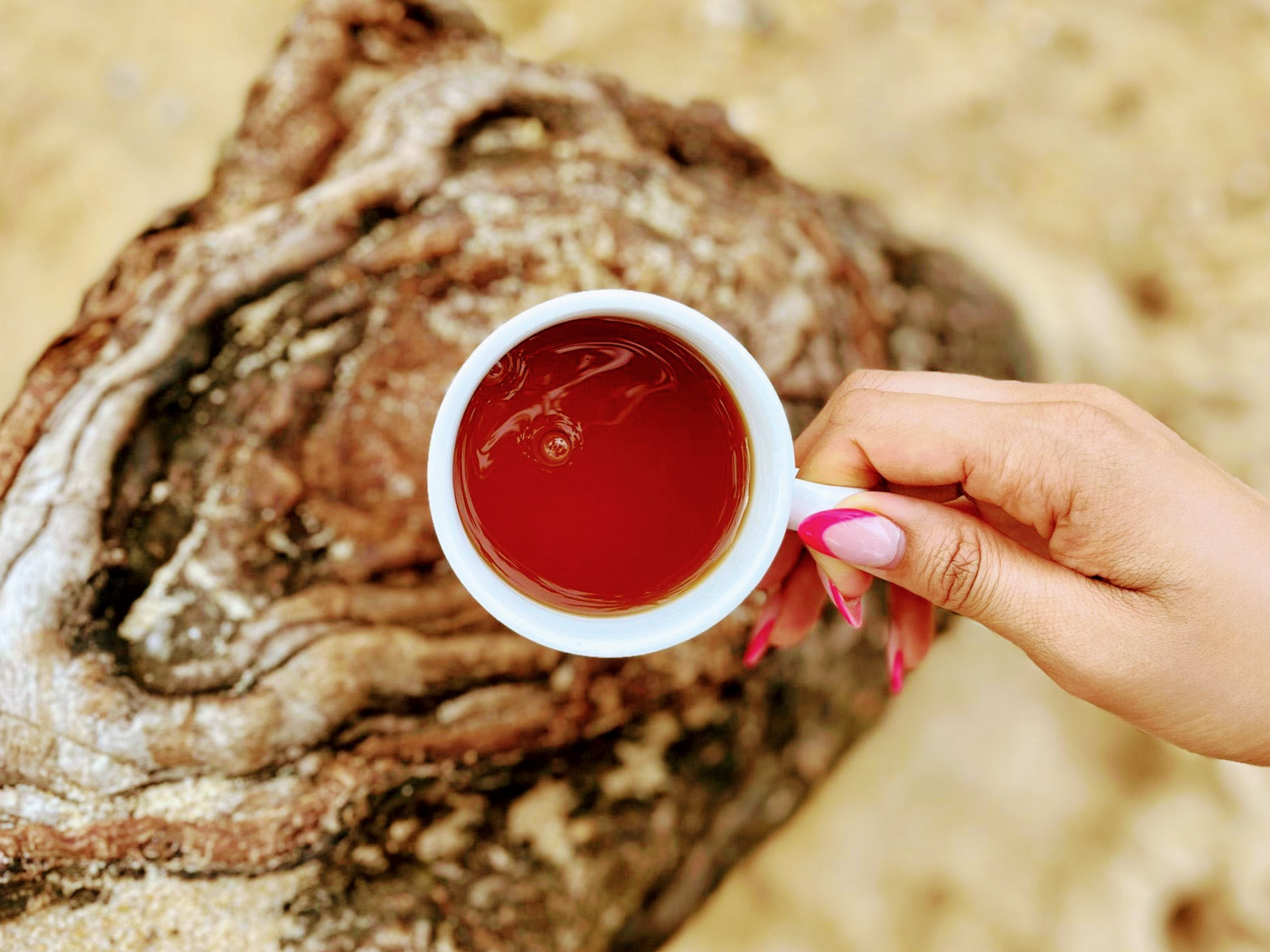 Holding a cup of SHE KITTY tea that provides relief for menopause symptoms. 